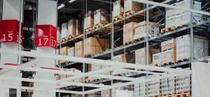 Tall shelving units in a large warehouse, filled with cardboard boxes.